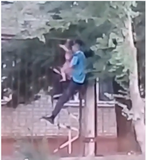В Запорожье пьяный мужчина с маленьким плачущим ребенком пытался перелезть через забор (ВИДЕО)